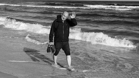 na zdjęciu trener Marek Maciejewski spacerujący po plaży. Zdjęcie czarno-białe