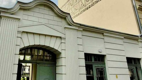 Zdjęcie przedstawia bramę wejściową do kamienicy w centrum miasta. Na górze napis informujący o spotkaniu konsultacyjnym na prowadzenie świetlicy artystycznej w Łodzi.
