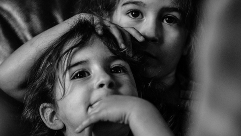 Czarno-białe zdjęcie przedstawiające twarze dwójki kilkuletnich dzieci.